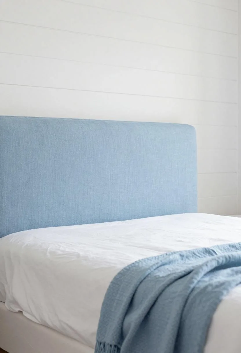 Pale blue linen upholstered headboard bed with crisp white cotton layers in morning light